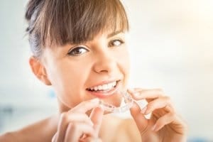 Woman putting in Invisalign clear aligners