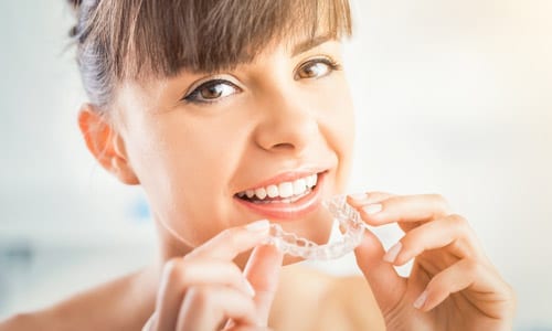 woman putting in Invisalign clear aligners